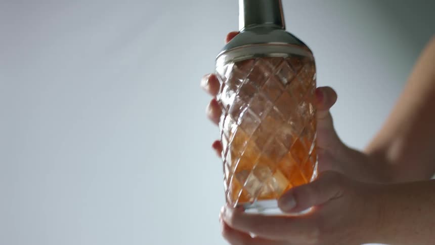 A bartender mixing a cocktail in a glass shaker