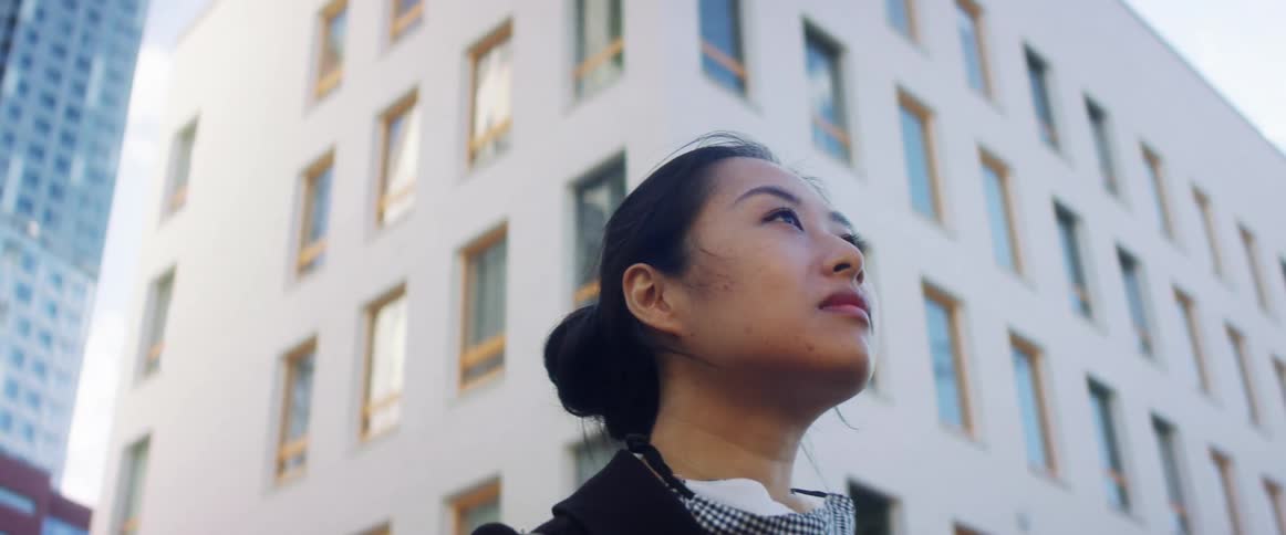 A woman stands in a downtown area by office buildings