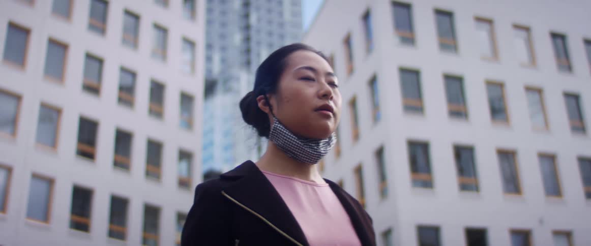 A woman is standing in a city while wearing a mask