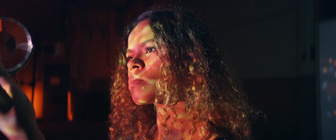 A woman holds a crystal up to her face and stares at it curiously