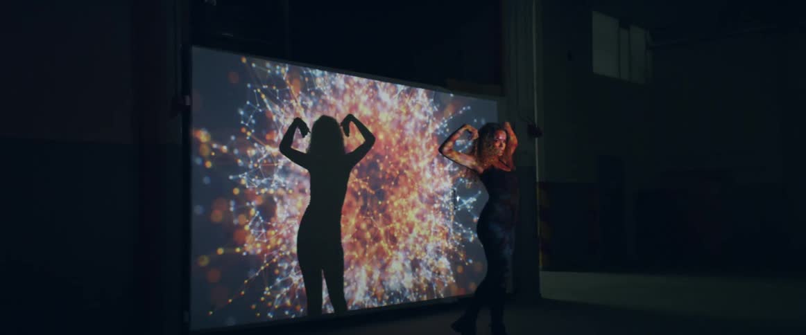 A young woman dancing in front of a large screen
