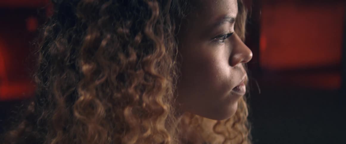 Side view of a black woman with curly brown hair looking around