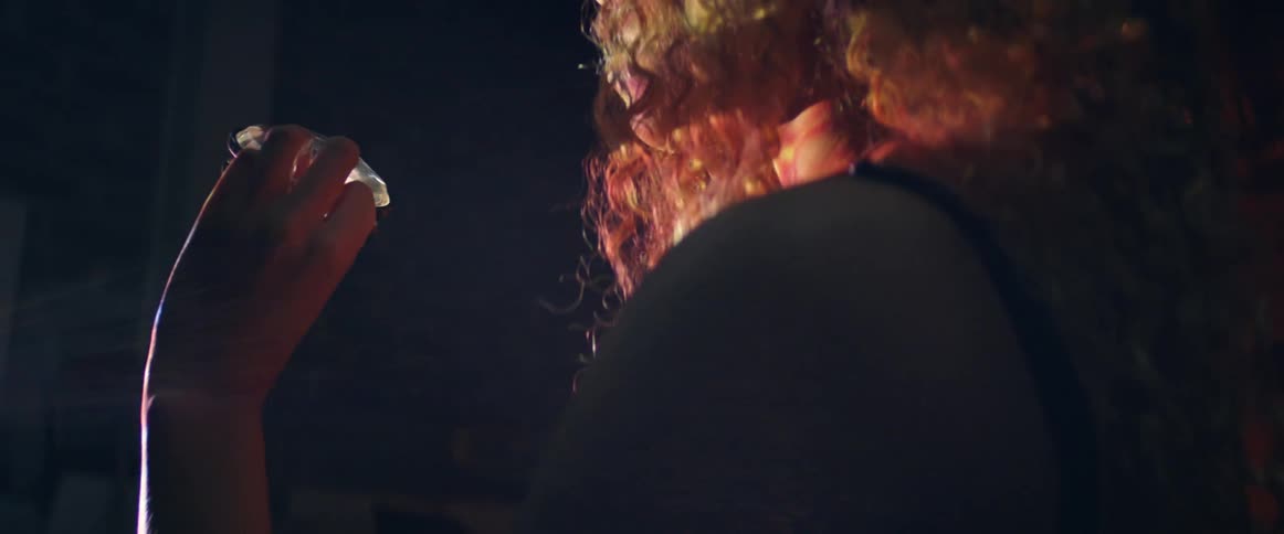 A woman looks at a piece of glass and watches the reflections it makes