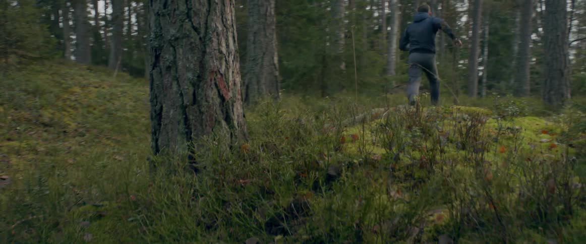 A man running quickly and awkwardly through a forest