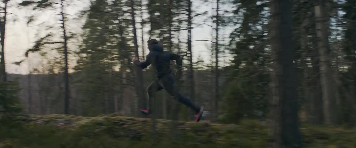 Man running on a trail through the forest at sunset