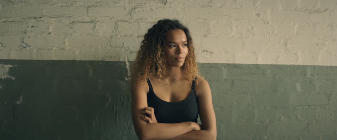 A woman folds her arms by the wall