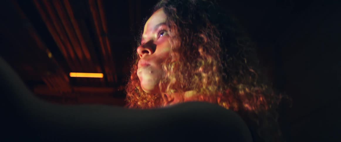 A woman standing inside of a building on a stage examines a shiny diamond like object in her hand