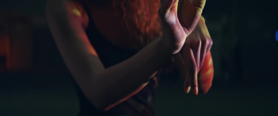 Young woman waves her hands in front of the camera on a dimly lit room