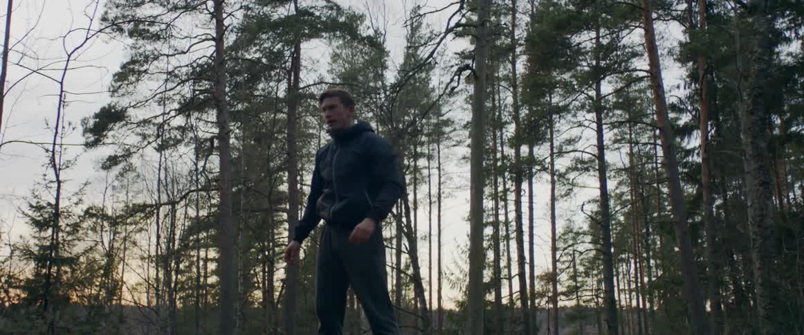 Man is running through the forest at sunset and stumbles then stops straightens up and breaths heavy