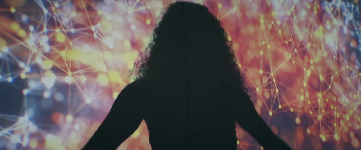 A teenage girl dances in front of a giant screen with space images on