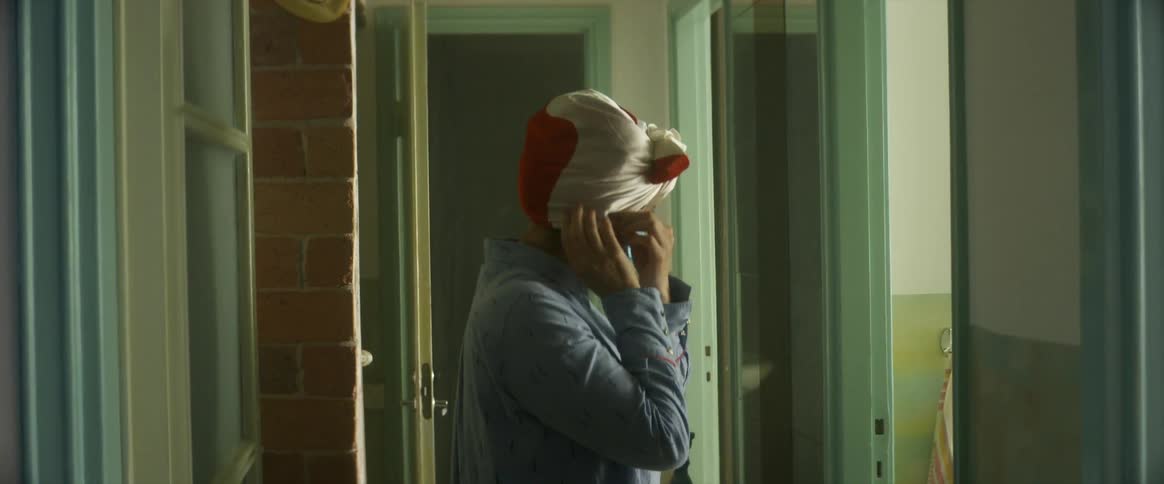 Woman with headscarf picking up a surgical mask opening it putting it on her ears pressing the nose piece and adjusting it on her face