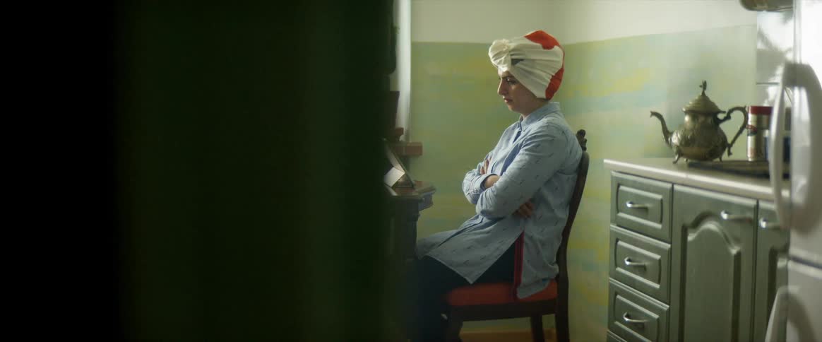 A woman sitting on a chair by a table looking at a tablet
