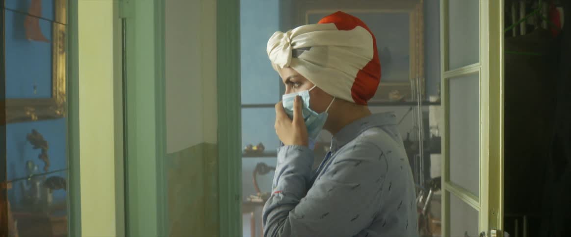 A woman at home puts a face mask on