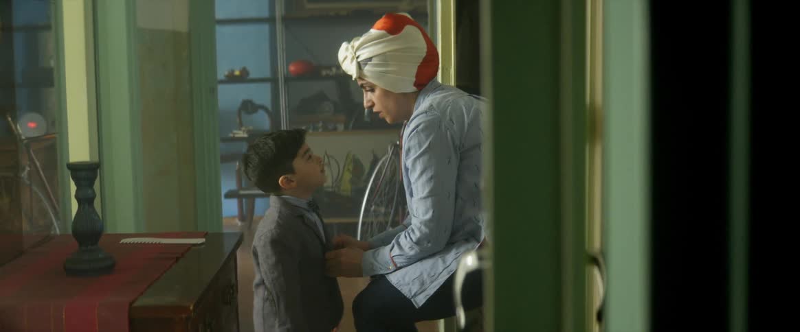 Mother dressing up her son with formal clothes at home