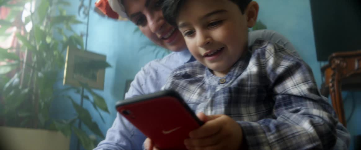 A woman holds her son in her lap as they look at a tablet together