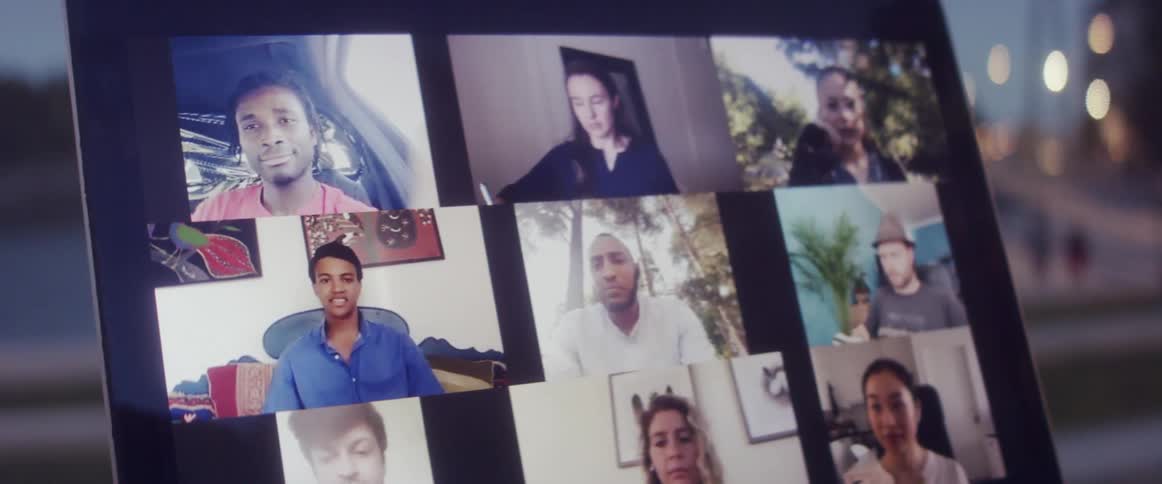 Person talks to others via video conferencing outdoors across form building showing lights