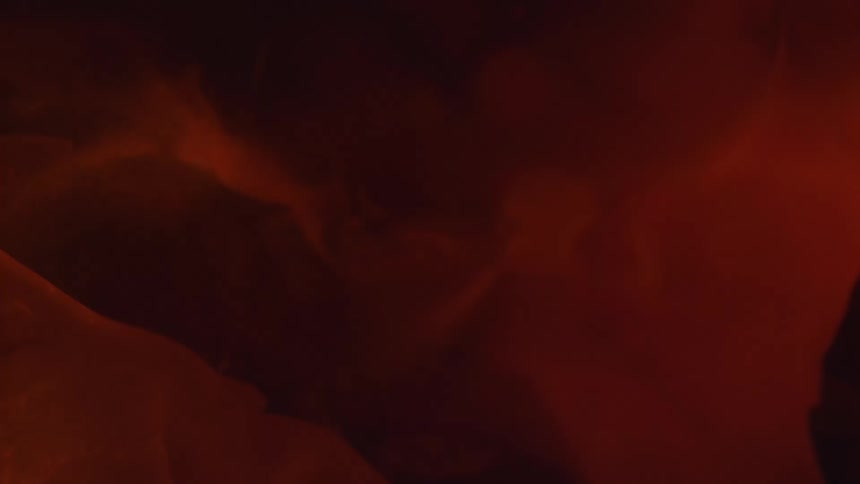 Red ink floating in waves on clear water in a dark room
