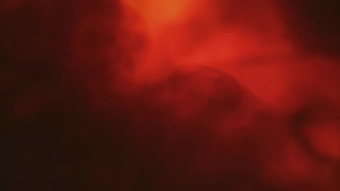 A thin cloud of smoke blows in front of an orange hued background