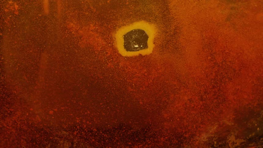 Clusters of yellow and orange particles move in a spiral motion slowly closing in a cap of yellow particles