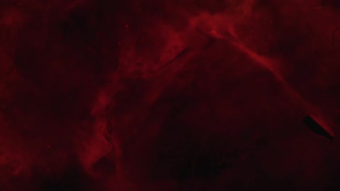 Red ink poured spreading in water over a surface