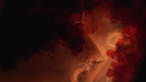 A crystal like substance appears submerged in some liquid as splashes of red are added in in large amounts