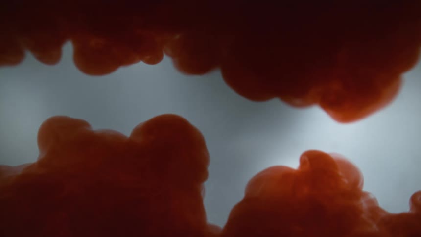 Red liquid moving and converging against a grey background