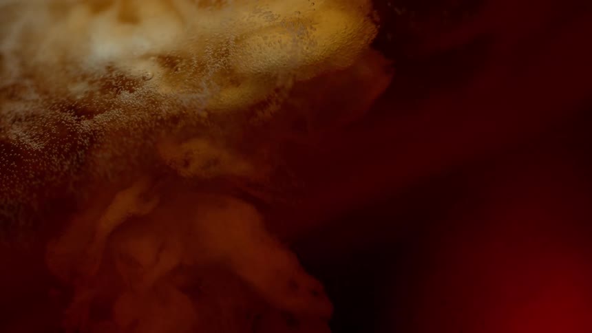 White foam as liquid meets amber liquid with bubbles dispersing