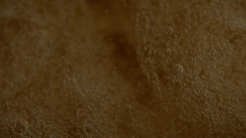 A red background turns to white foam with bubbles moving downward and dissipating