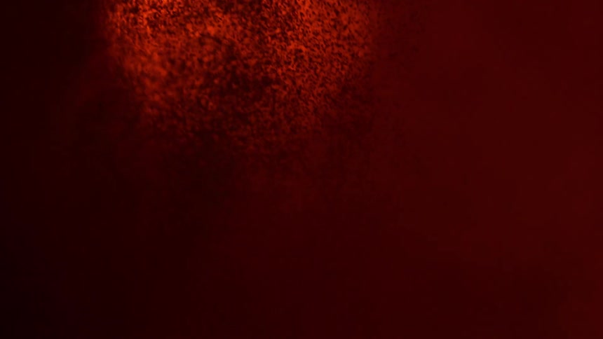 Red powder is dropped into a vat of liquid