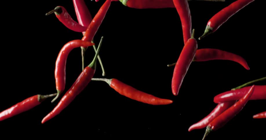 Red chili peppers being tossed with a black background
