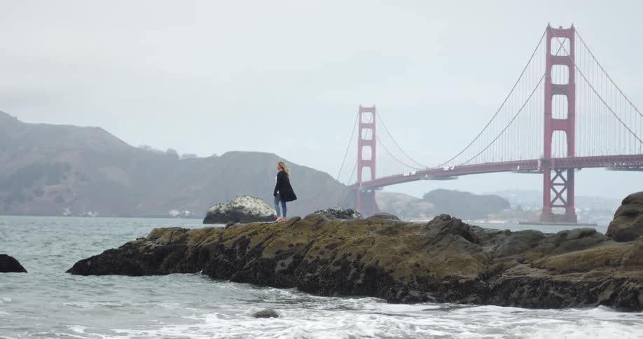 A woman standing on the shore and looking out at the water