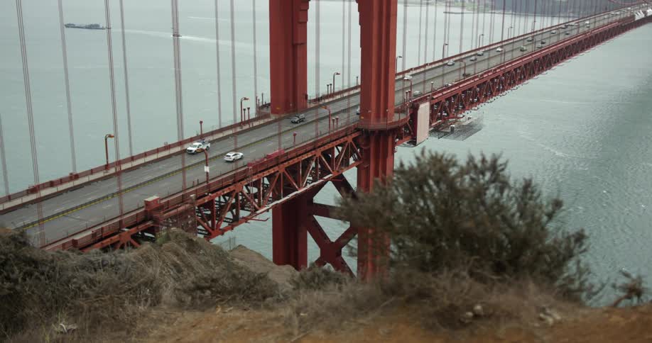 Traffic crosses golden gate bridge on windy day as ship moves away leaving wake