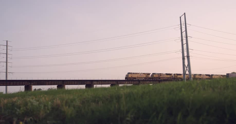 A train driving on a track over a grassland