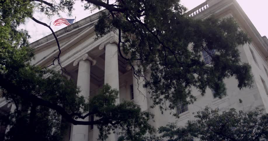 An american flag flies above a government building with large white columns
