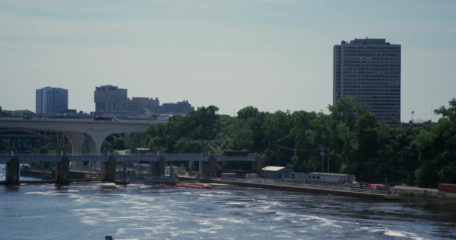 A layer of melting ice and snow covers the top of a river that runs through a city