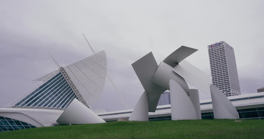 White abstract art located in front of a building on green glass on an overcast day