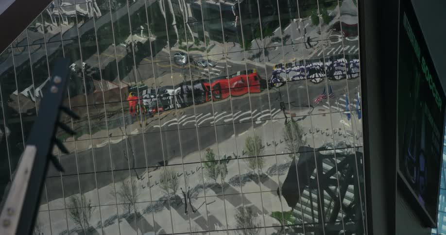 A passenger train is reflected on the mirrored windows of a high rise building