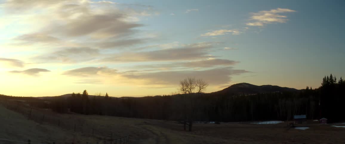 Sun sets in a cloudy sky over the countryside