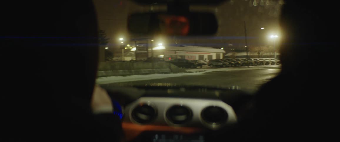 Person driving a car with a passenger on a winter night with wet streets
