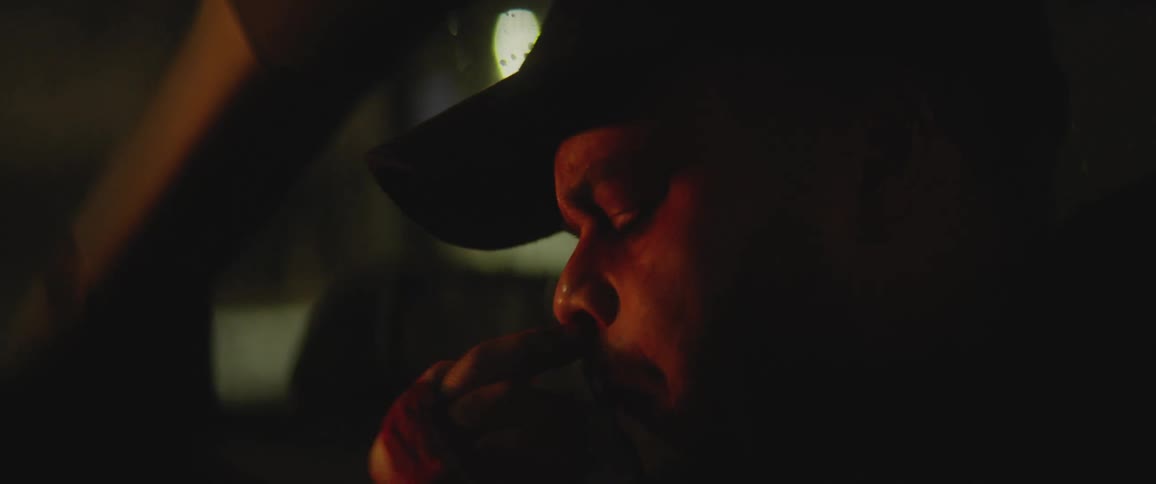 Man with bloody hand touches nose sitting in car moving through city at night