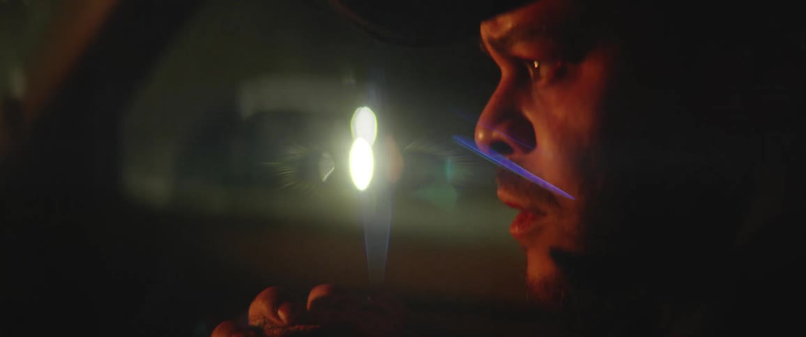 An anxious man with a bloody cloth wrapped around one fist rides in the passenger seat of a vehicle as it travels at night