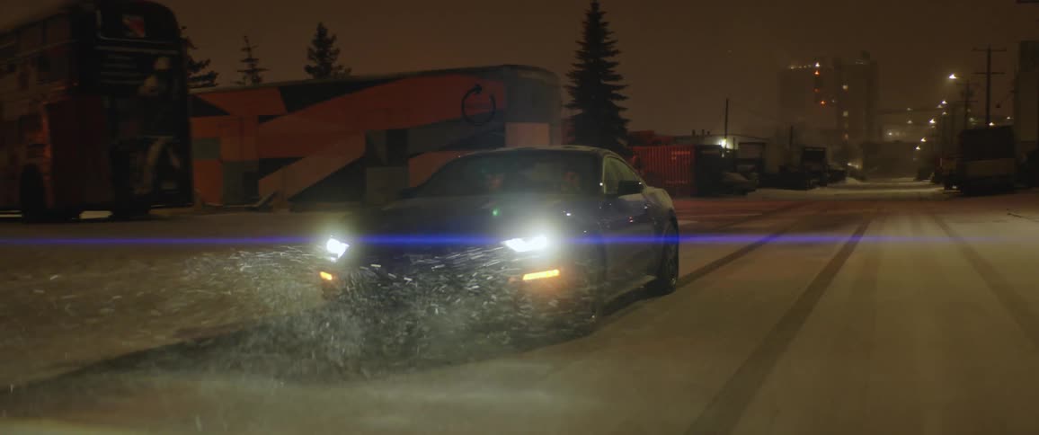 People driving down a road at night as the snow falls