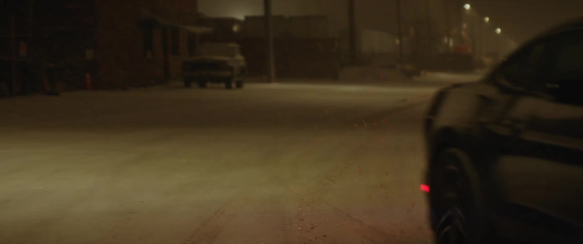 A car is driving on a road at night