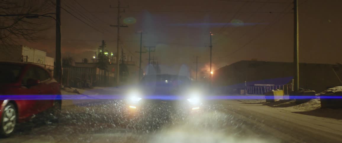 A car is driving on a road at night
