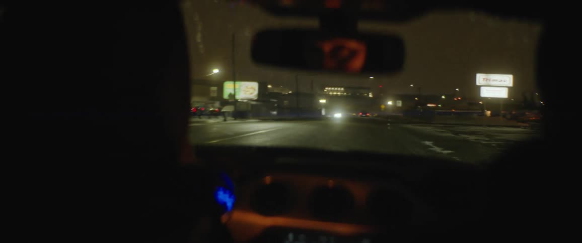 Two people driving through a city at night