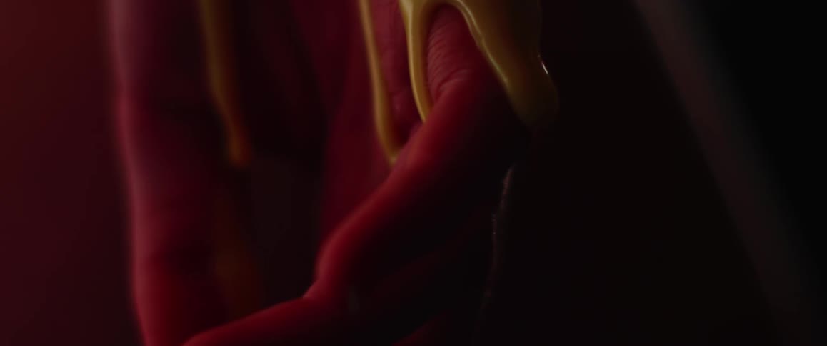 A streak of yellow slime falls down a red colored hand and drips off