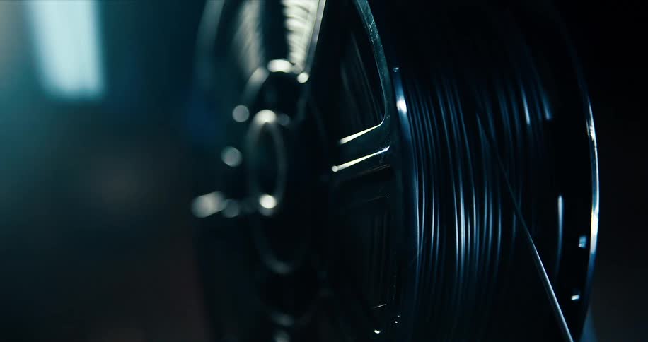 A black spool of black cable is being spun slowly with a tightening of one cable being pulled