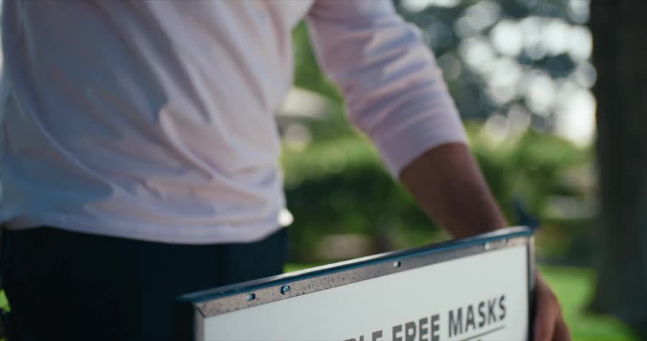 A man hammering a sign in to a lawn