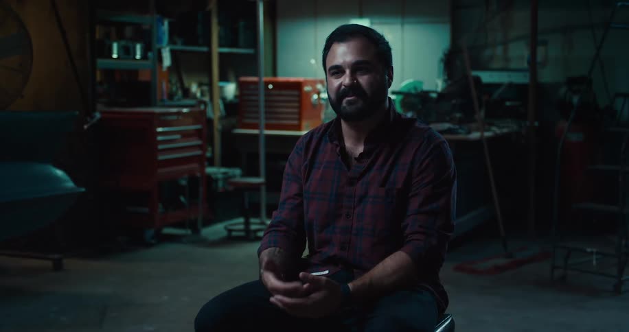 A man is sitting in a building while talking and moving his hands