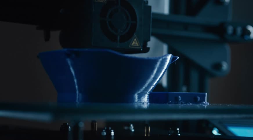 A machine works on a plastic item appearing to carve it into shape along a conveyor belt